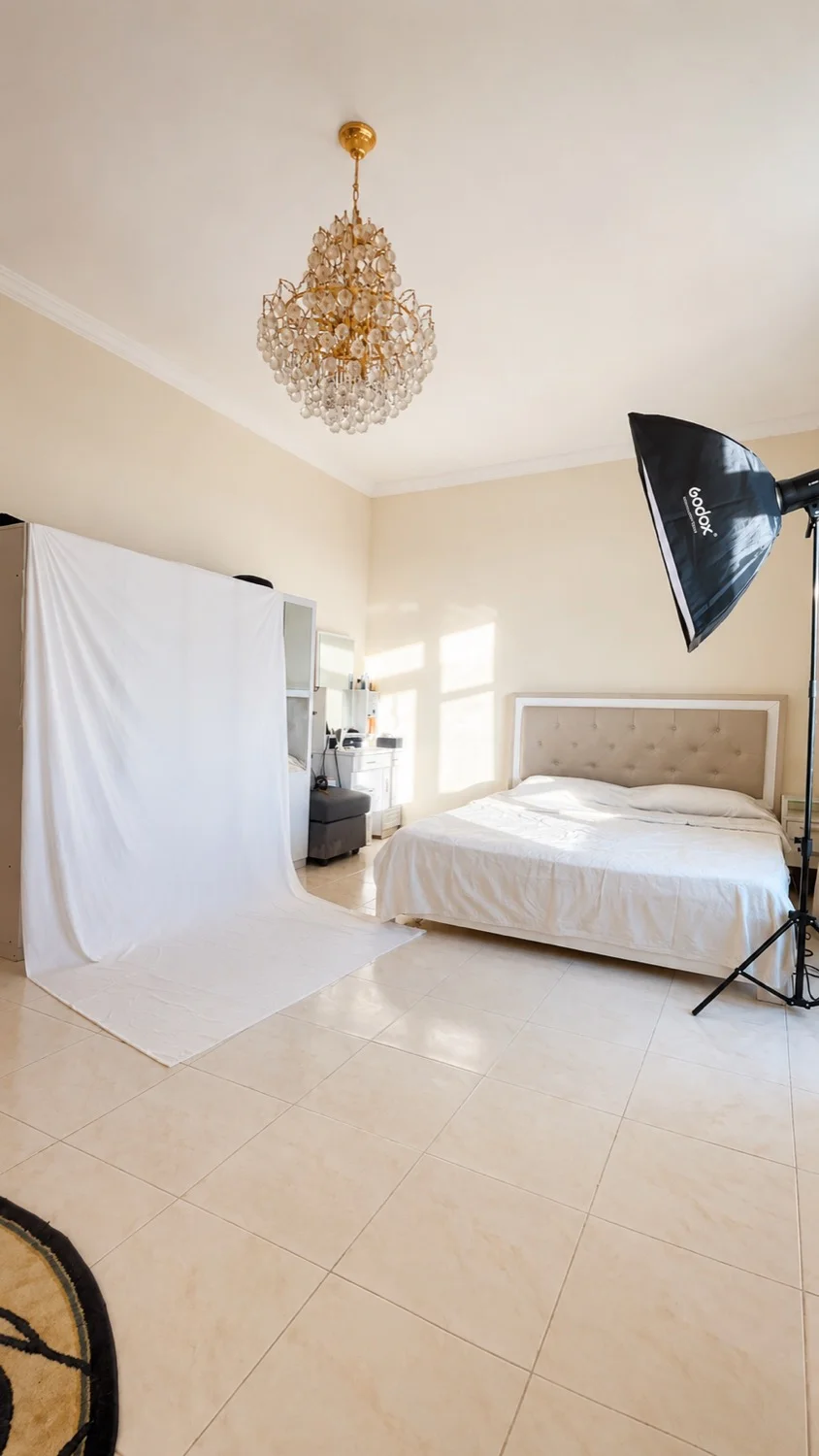A bedroom in a Dubai Airbnb converted into a makeshift studio with a white backdrop and Godox softbox