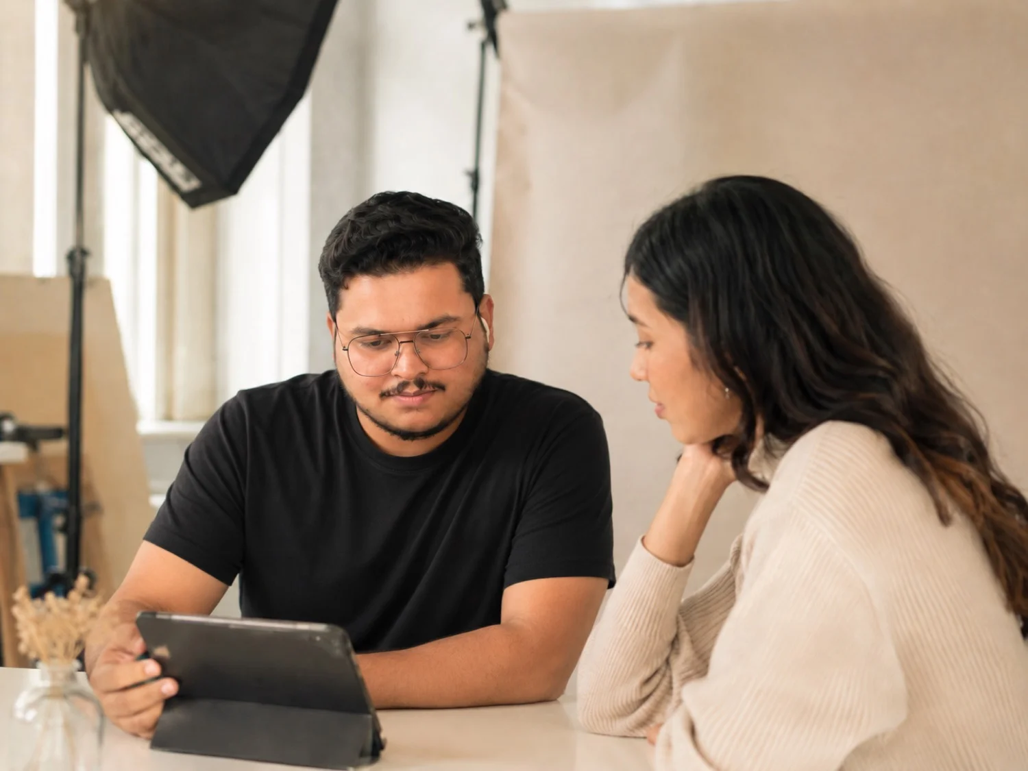 Photographer and model sitting together reviewing a shot plan on a tablet before a photoshoot