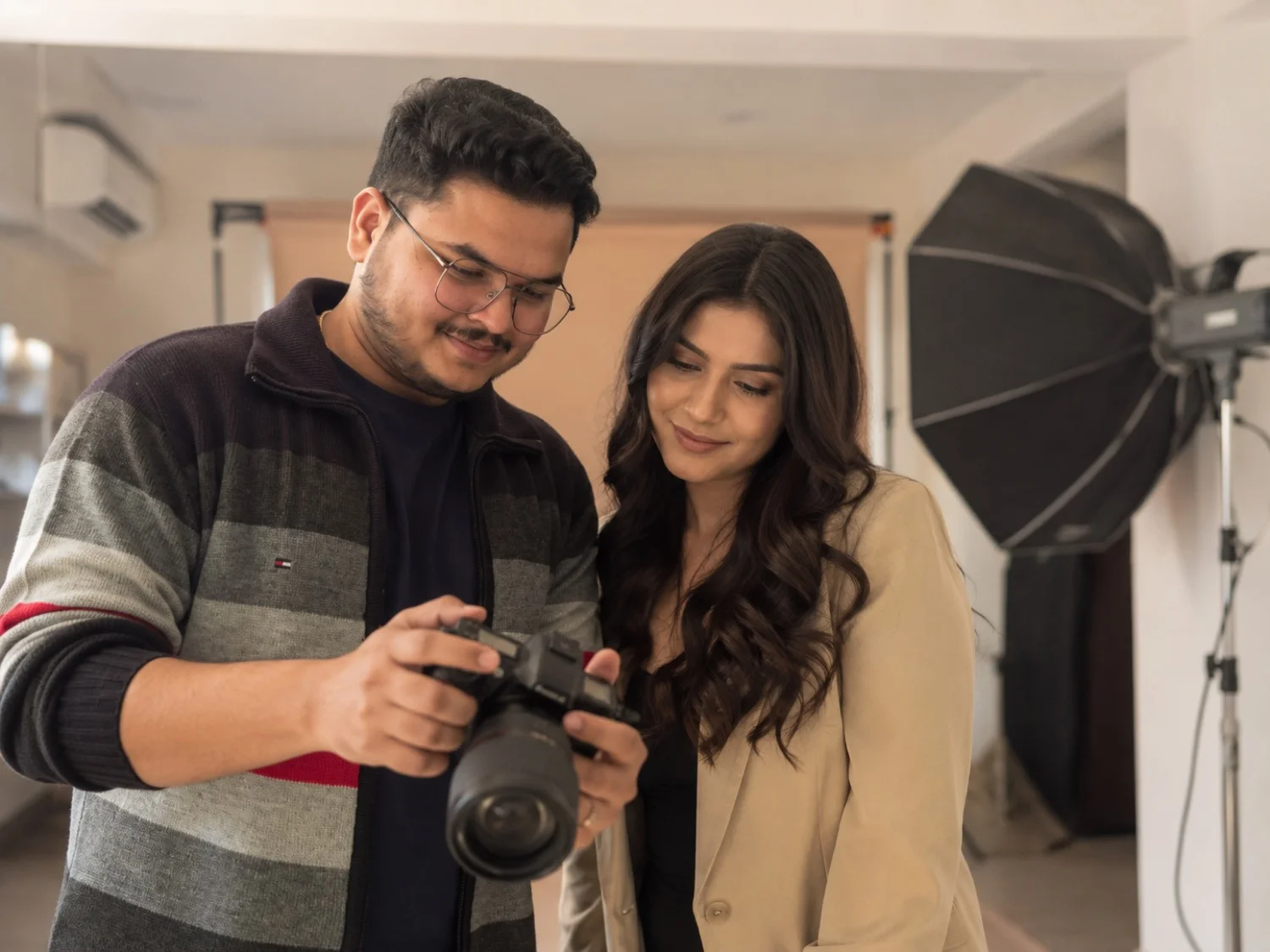 Photographer and model looking together at photos on the camera's back screen mid-shoot