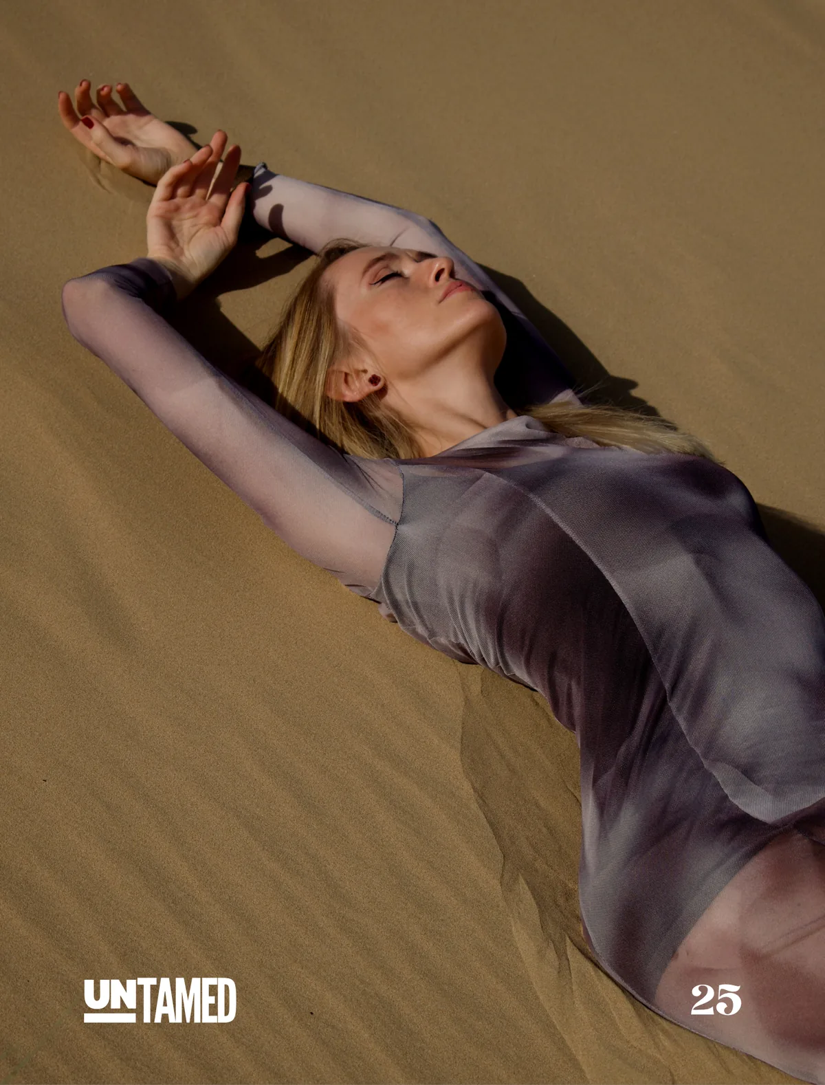 Model Olga lying in the sand with arms raised, UNTAMED Magazine editorial by Photoczaro